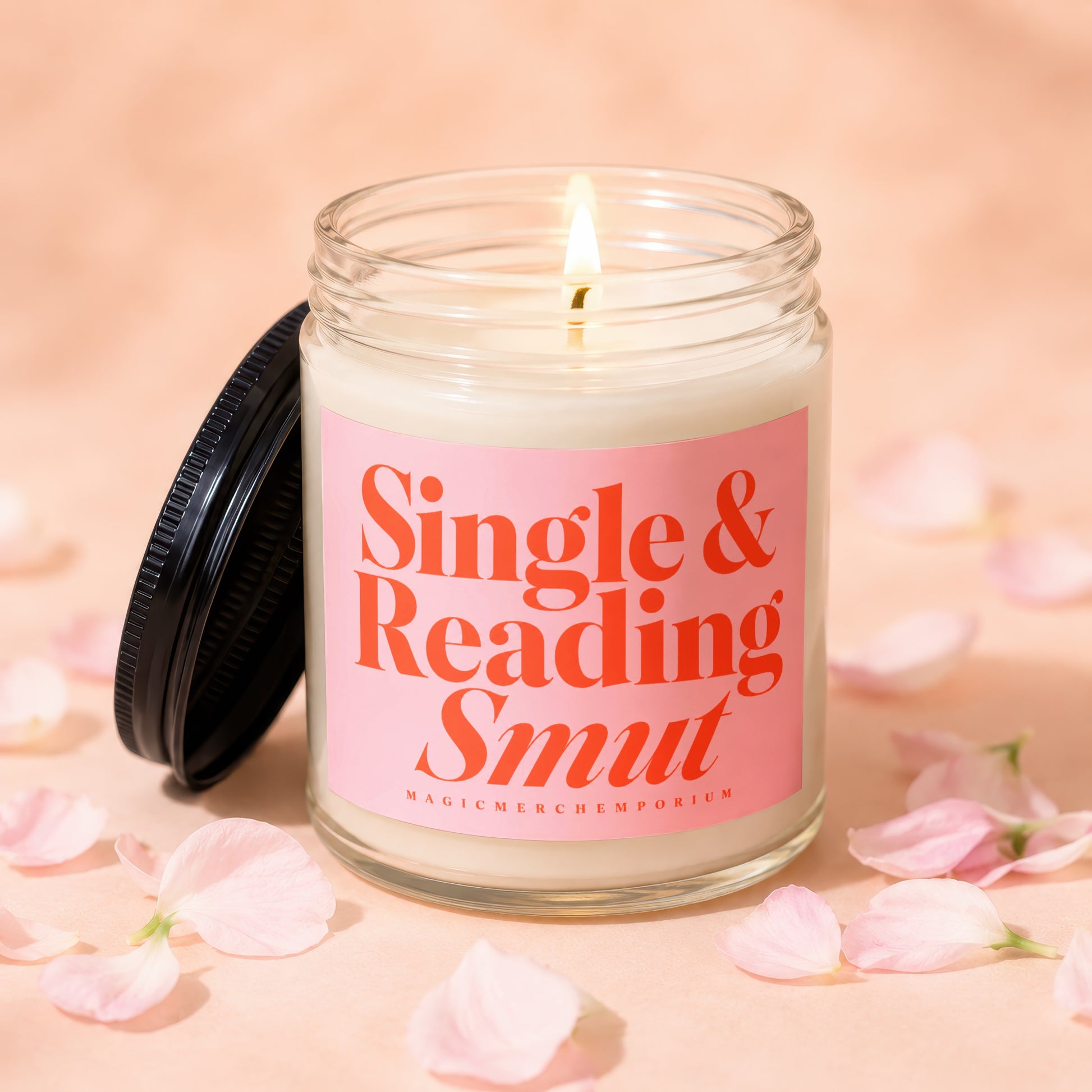 Glass candle with lit wick and "Single & Reading Smut" text on pink label.
