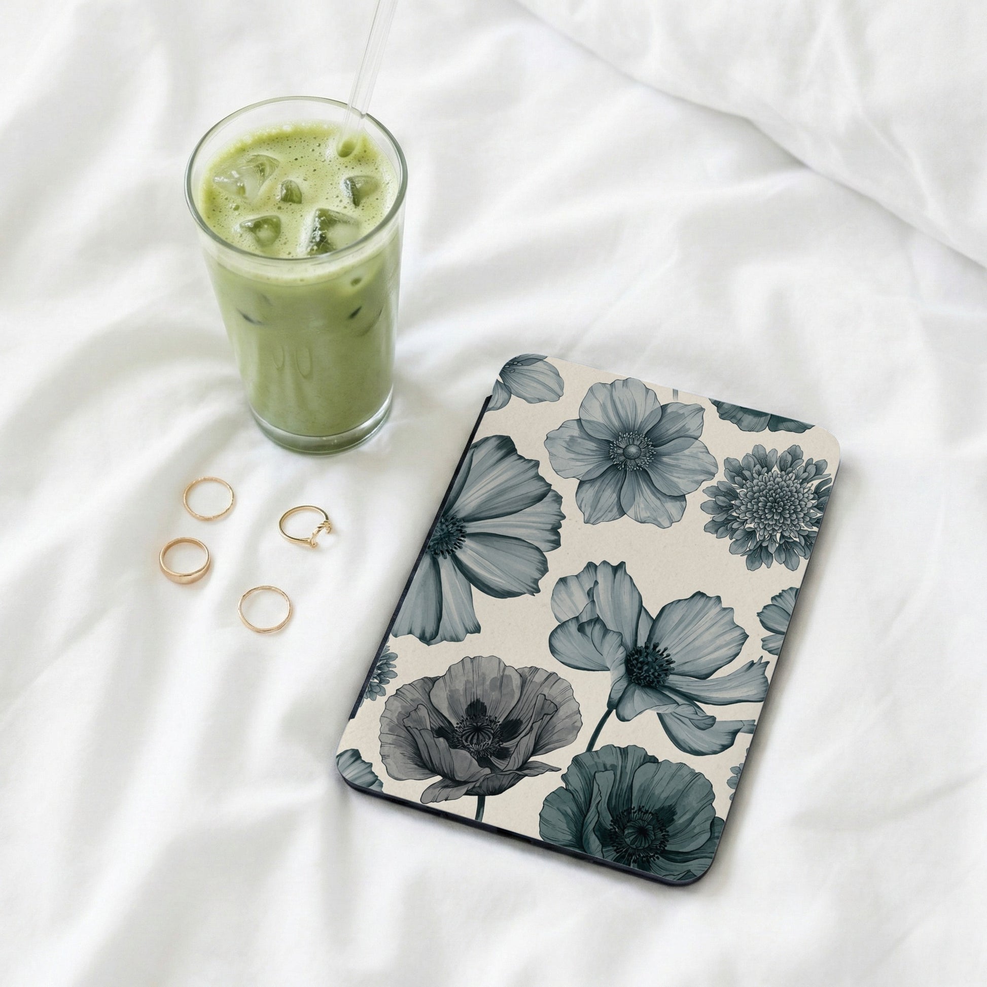 Floral patterned tablet cover with a glass of iced matcha latte and gold rings.