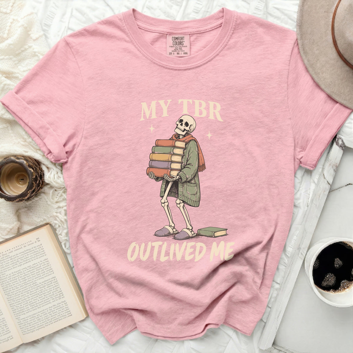 Pink t-shirt with skeleton holding books, text reads "MY TBR OUTLIVED ME".