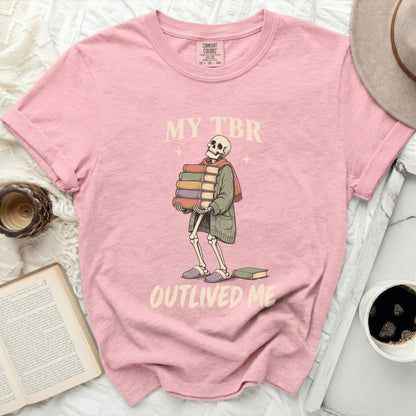 Pink t-shirt with skeleton holding books, text reads "MY TBR OUTLIVED ME".