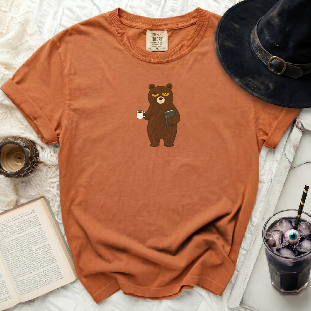 Orange t-shirt with grumpy bear holding coffee and book.