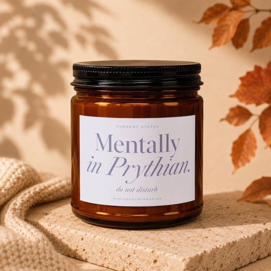 An amber glass jar candle with a black lid and white label reading Mentally in Prythian.
