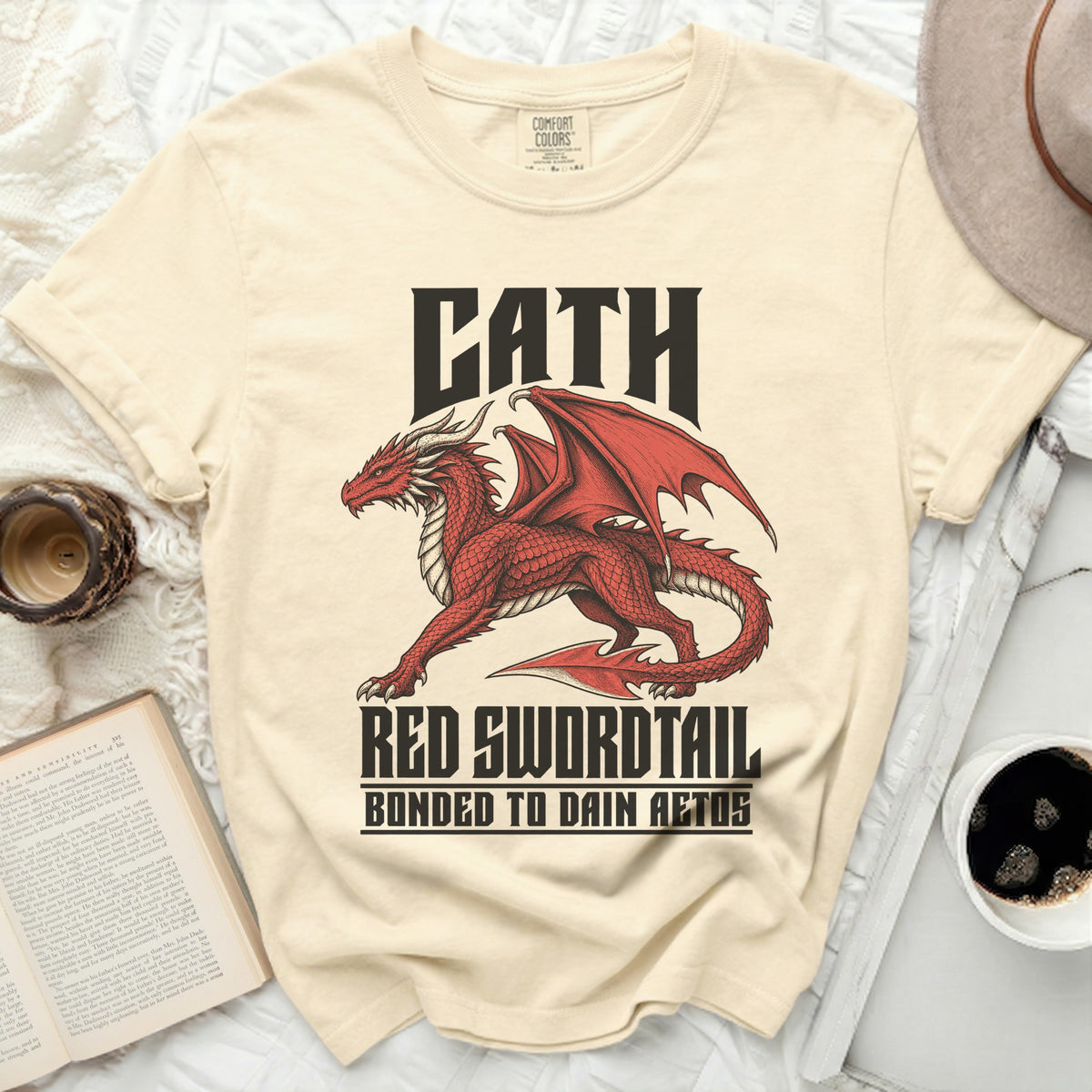 Cream t-shirt with a red dragon graphic and text "CATH RED SWORDTAIL BONDED TO DAIN AETOS".
