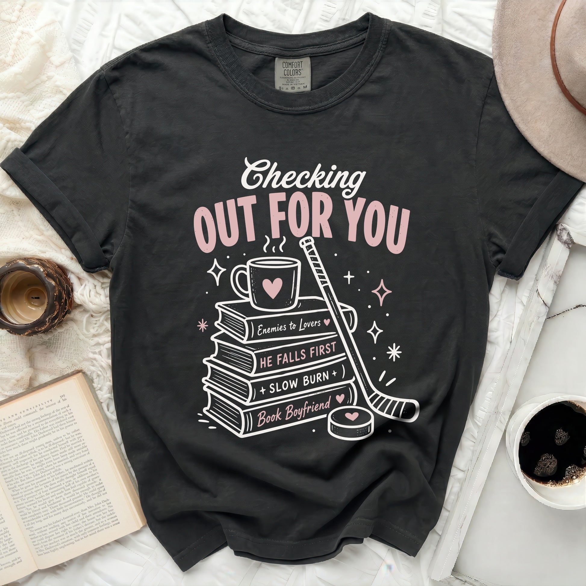 Black t-shirt with pink text "Checking Out For You" and book/hockey graphics.