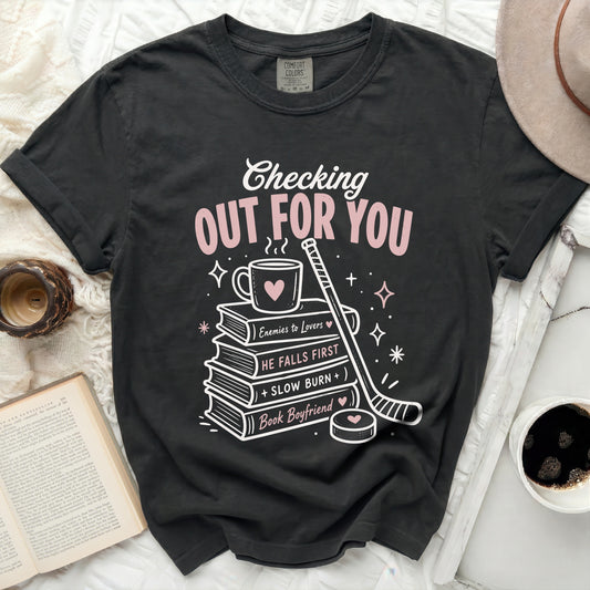 Black t-shirt with pink text "Checking Out For You" and book/hockey graphics.