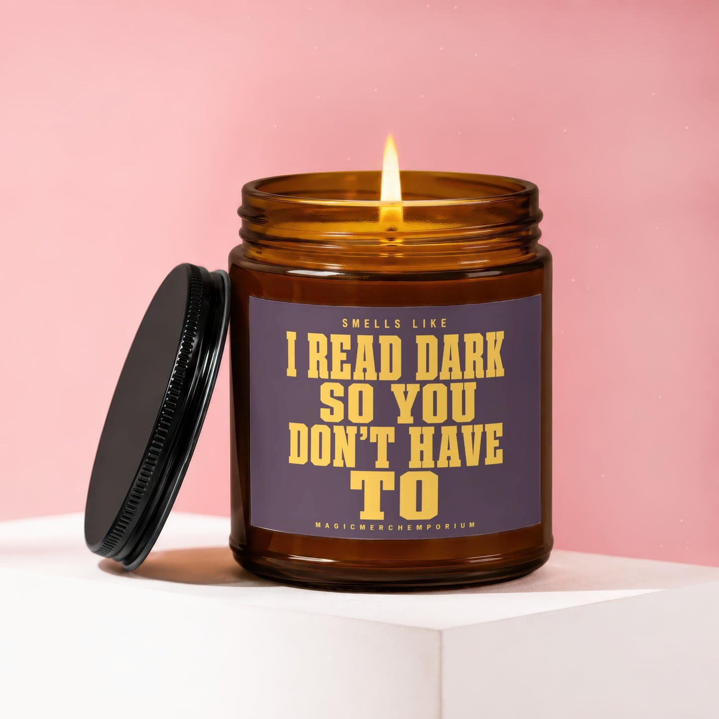 Amber candle with lit flame and dark lid reads "Smells like I read dark so you don't have to".