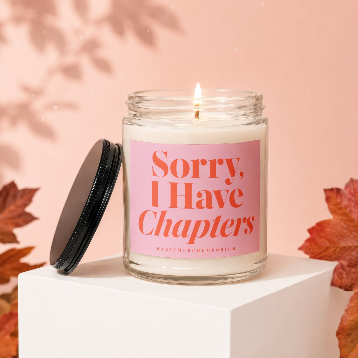 Scented candle with "Sorry, I Have Chapters" text on a light pink label.