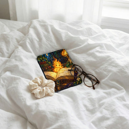 Open book with fantasy art, glasses, and scrunchie on white bedding.