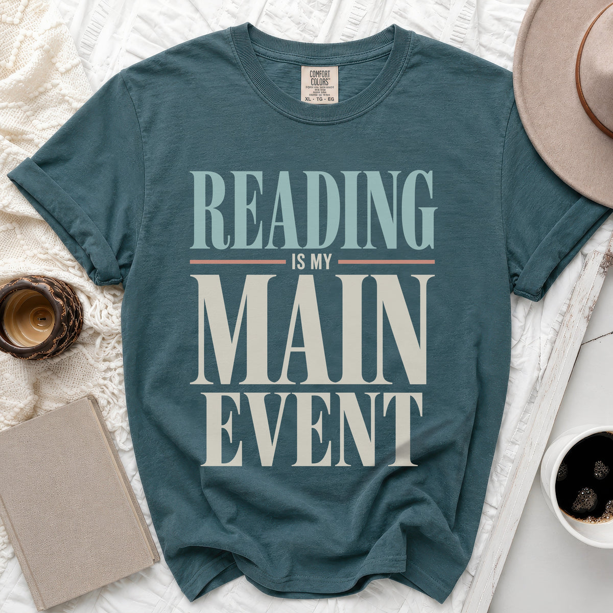 Teal t-shirt with "Reading Is My Main Event" text in cream and blue.