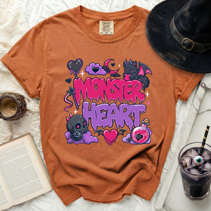 Orange t-shirt with "Monster Heart" graphic, clouds, bat, and potion bottle.