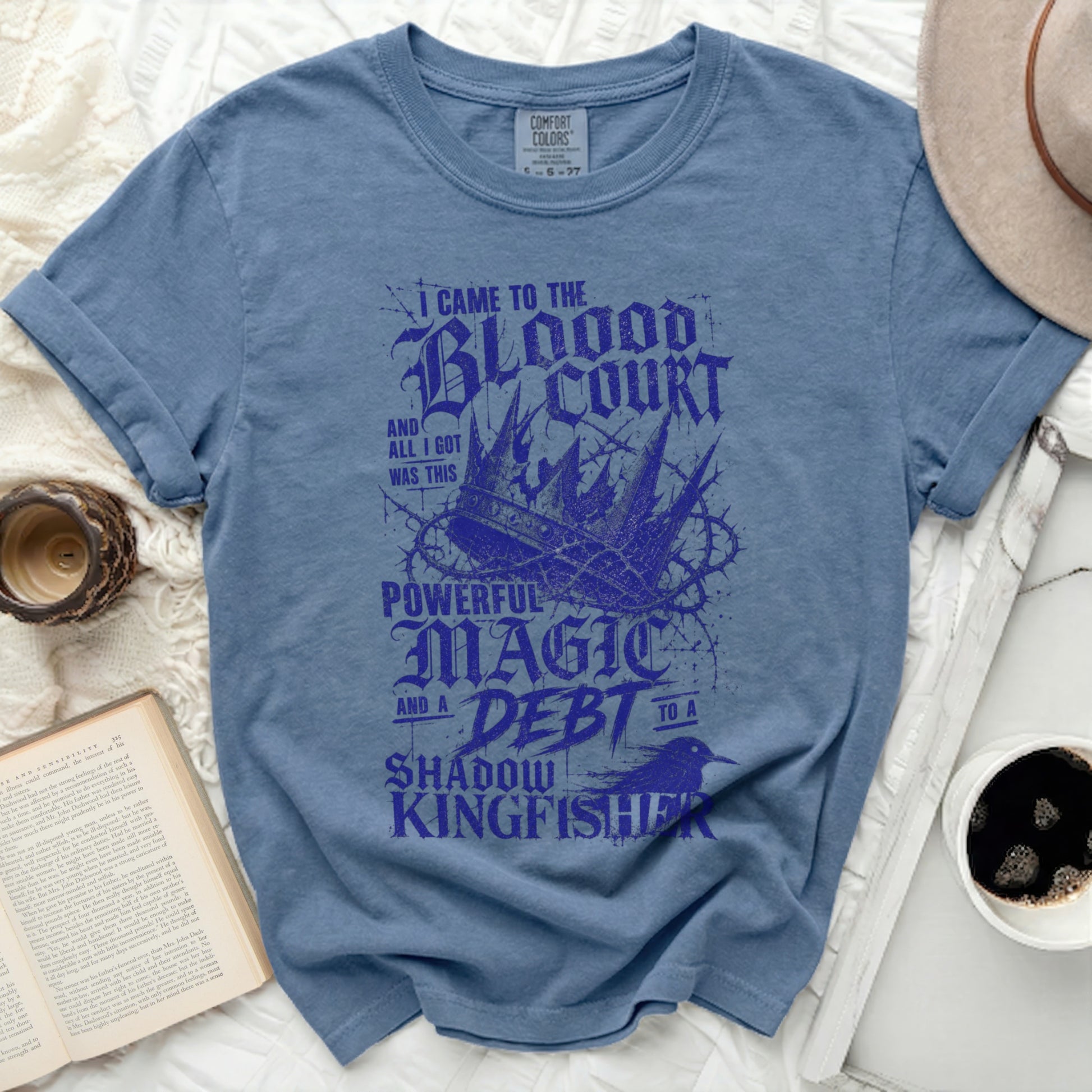 Blue t-shirt with "Blood Court, Powerful Magic, Debt to a Shadow Kingfisher" text.