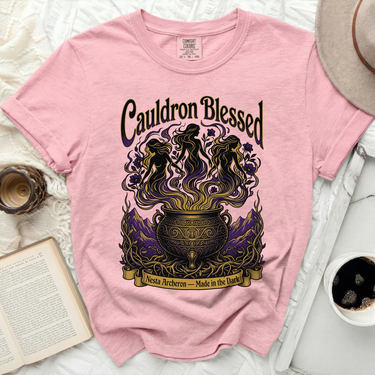 Pink t-shirt with "Cauldron Blessed" and three women dancing around a cauldron.