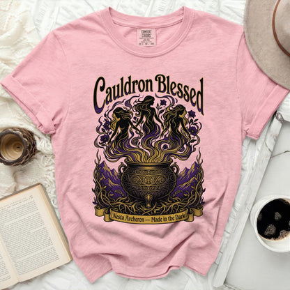 Pink t-shirt with "Cauldron Blessed" and three women dancing around a cauldron.