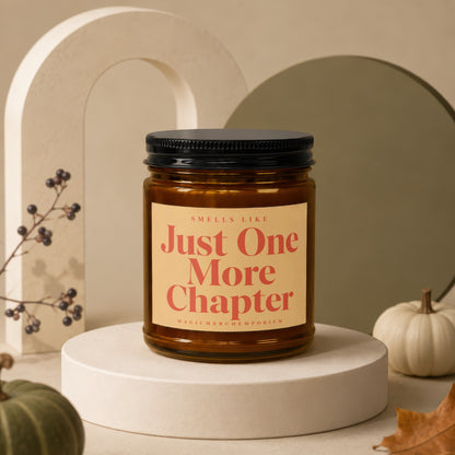 Amber jar candle with "Just One More Chapter" text and a black lid.