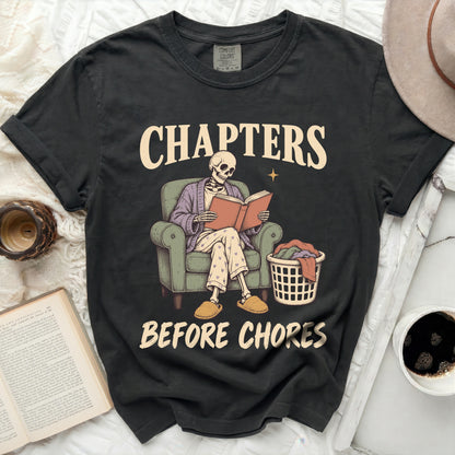 Skeleton reading a book in a chair, with laundry basket, text "CHAPTERS BEFORE CHORES".