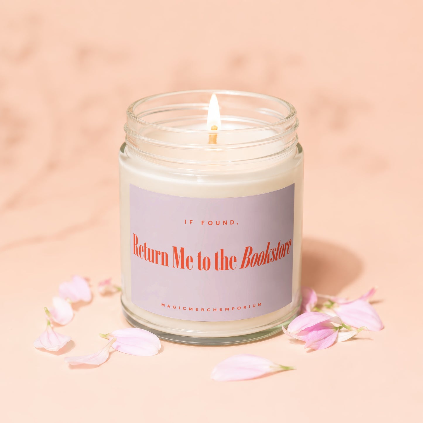 Jar candle with lit wick and purple label reading "IF FOUND, Return Me to the Bookstore".