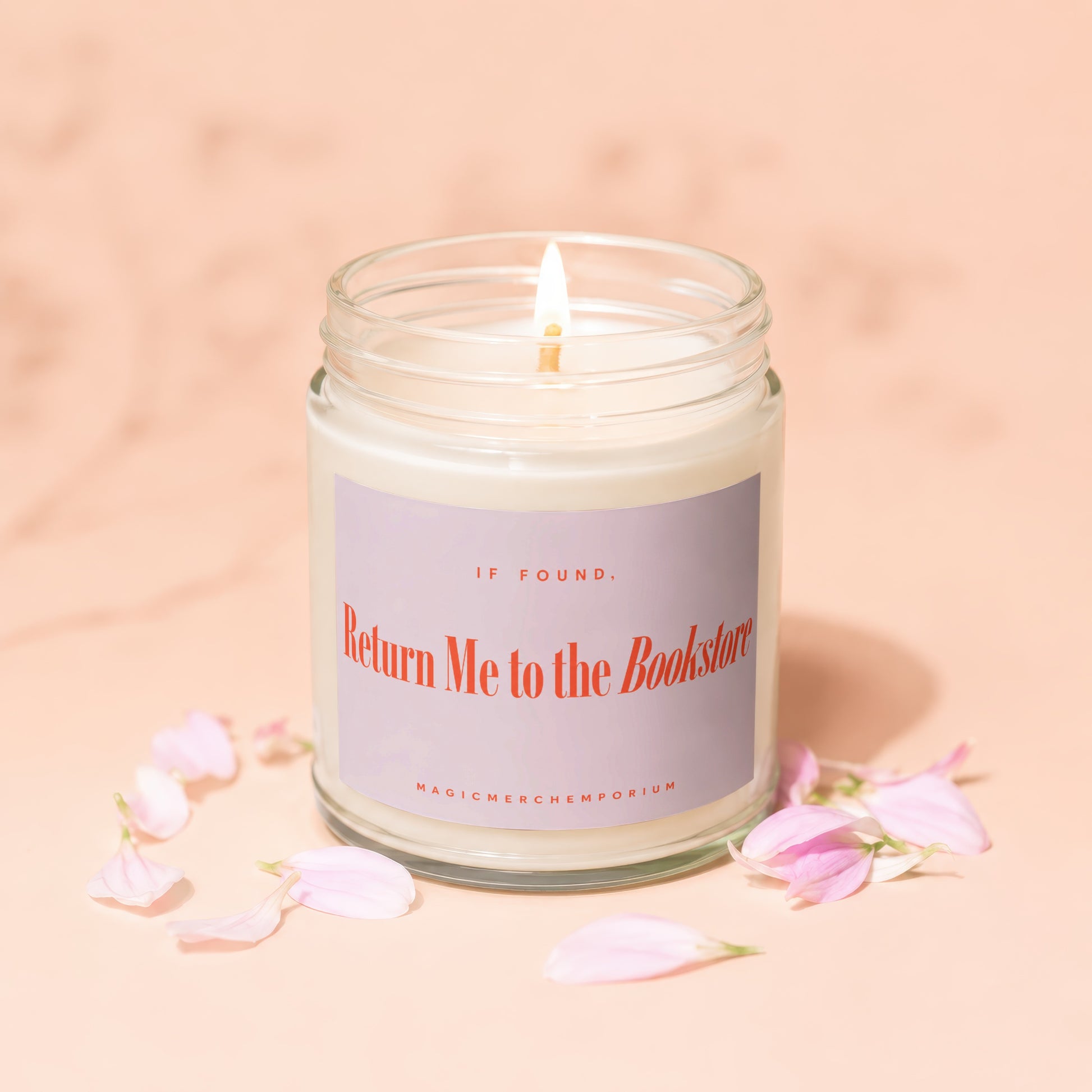 Jar candle with lit wick and purple label reading "IF FOUND, Return Me to the Bookstore".