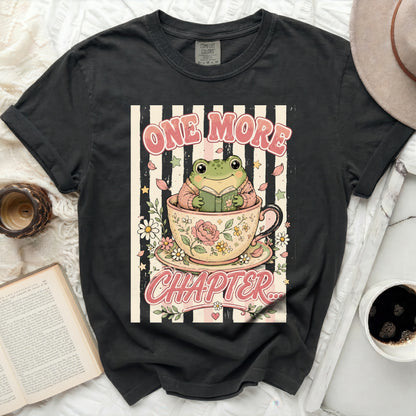 T-shirt with a frog reading a book in a teacup, text "ONE MORE CHAPTER".
