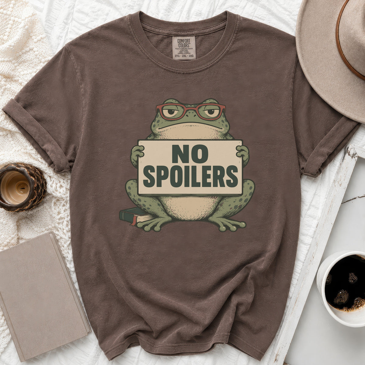 Brown t-shirt with a frog wearing glasses holding a "NO SPOILERS" sign.