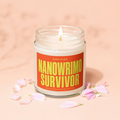 Lit candle in a glass jar with an orange label reading "CERTIFIED NANOWRIMO SURVIVOR".