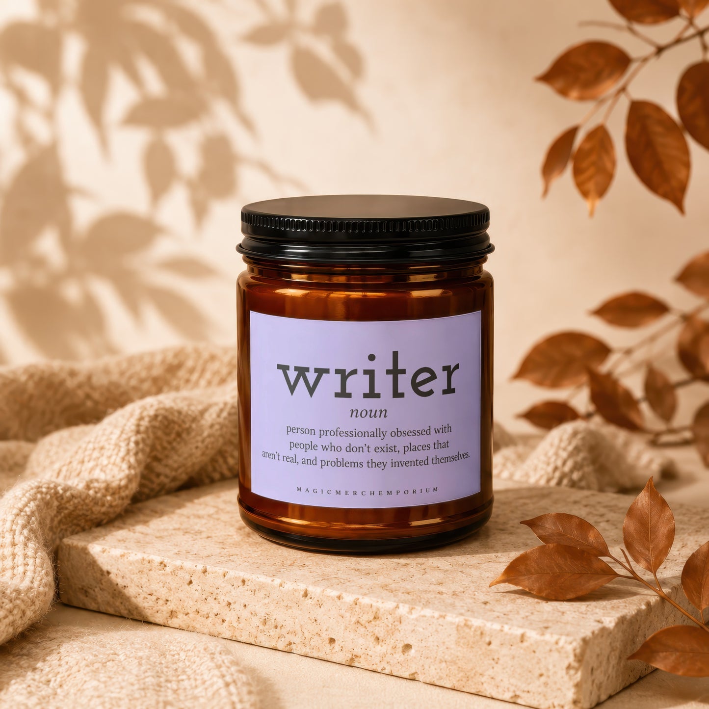 Candle with "writer" definition label, dark lid, amber jar, on stone.