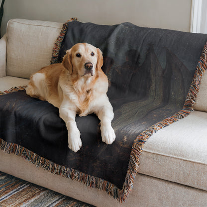 A golden retriever dog is lying on a black and gray blanket on a beige couch.