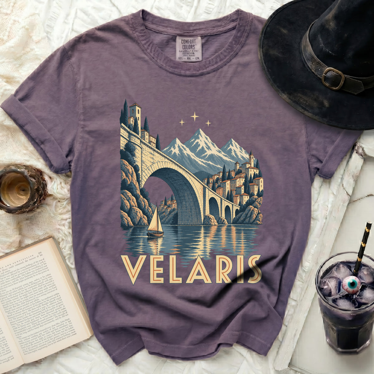 Purple t-shirt with a print of Velaris, a city with a bridge and mountains.