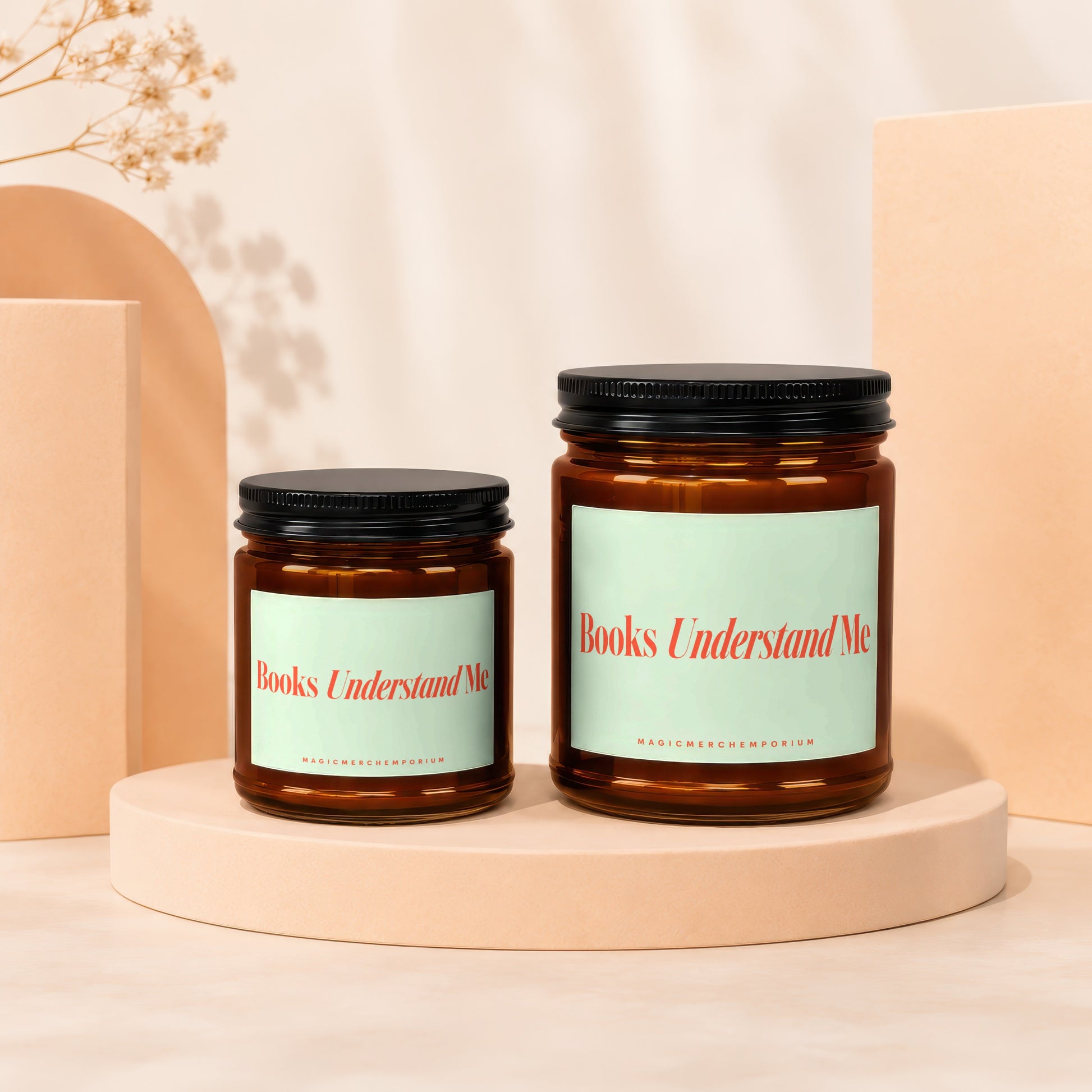 Two amber glass candles with black lids, each with a light green label that reads "Books Understand Me".