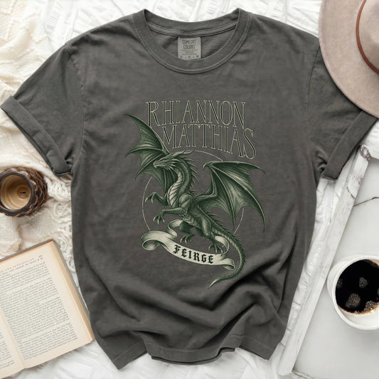 Dark gray t-shirt with "Rhiannon Matthias" and a green dragon on a banner reading "Feirge".
