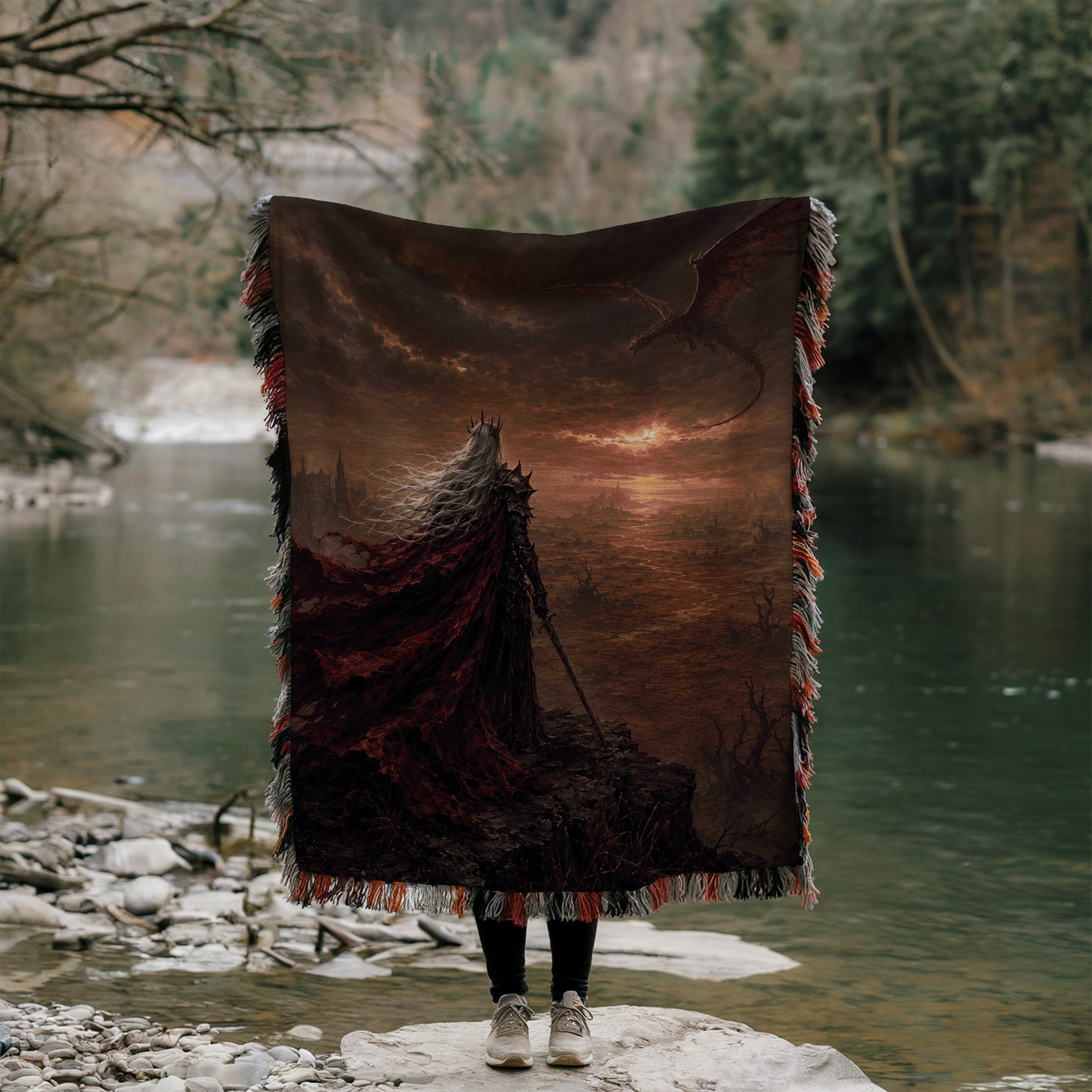 A person stands on a rock, holding a large tapestry or blanket that features a dragon and a sunset landscape.