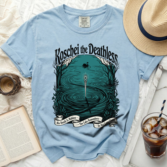 Light blue t-shirt with graphic: Koschei the Deathless, sword in lake, swan, and text.
