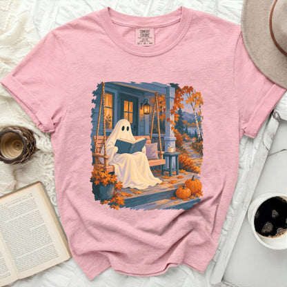 Ghost reading a book on a porch swing with pumpkins and autumn leaves.