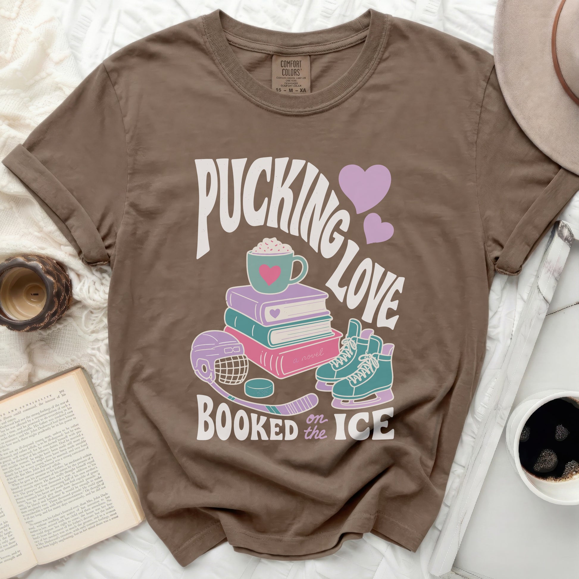 Brown t-shirt with "Pucking Love Booked on Ice" text and hockey theme graphics.