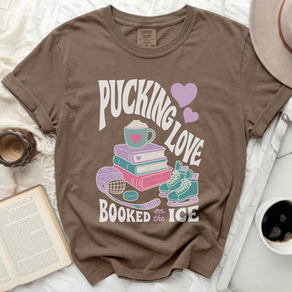 Brown t-shirt with "Pucking Love Booked on Ice" text and hockey theme graphics.