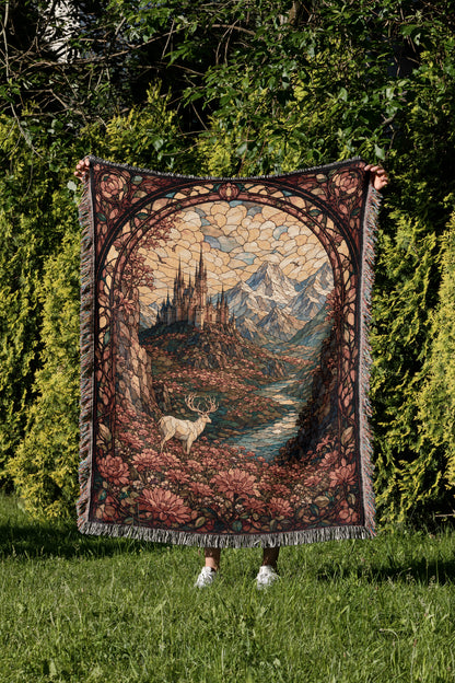 A person is holding up a large, ornate tapestry depicting a castle and a deer in a lush, forested landscape.