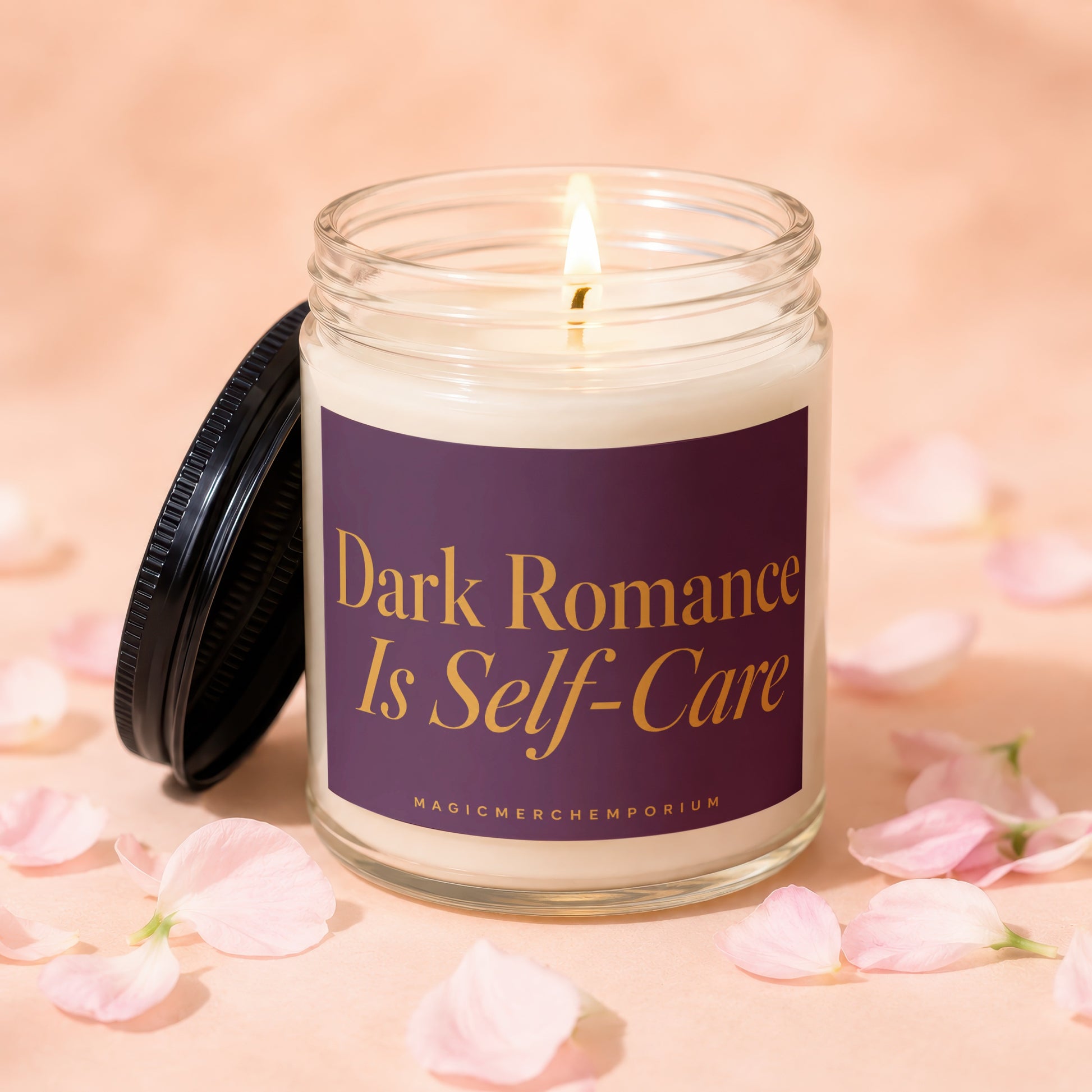 A lit candle in a glass jar with a dark purple label that reads "Dark Romance Is Self-Care."