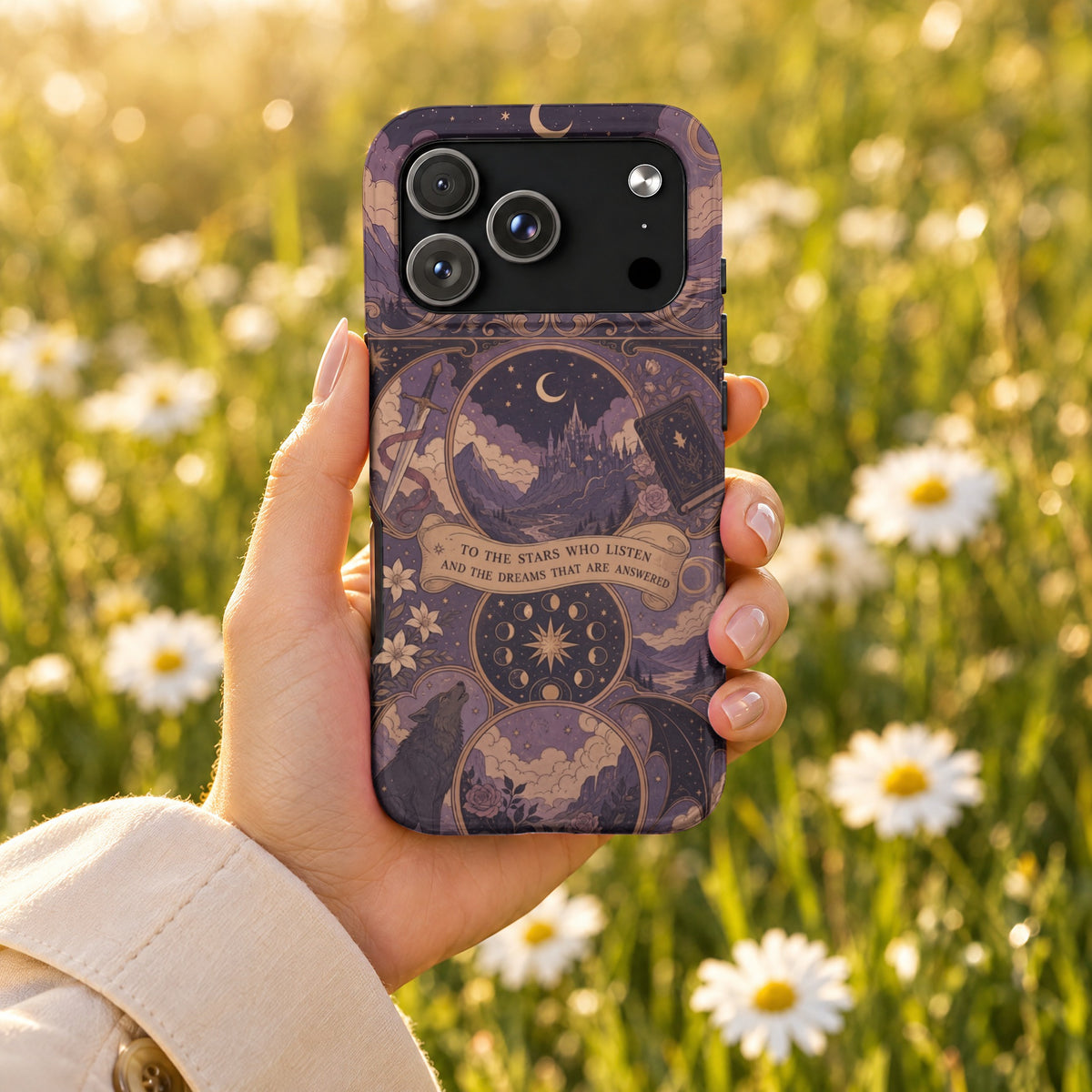 A hand holds a purple fantasy-themed phone case against a blurry background of white daisies.