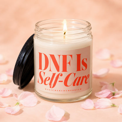 Glass candle with lit wick, featuring text "DNF Is Self-Care" and "MAGICMERCHIMPORIUM".