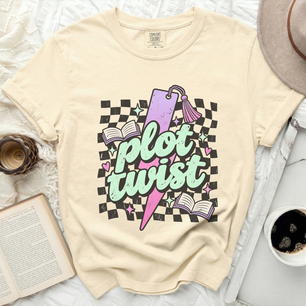 Cream t-shirt with "plot twist" text, lightning bolt, bookmark, and books.