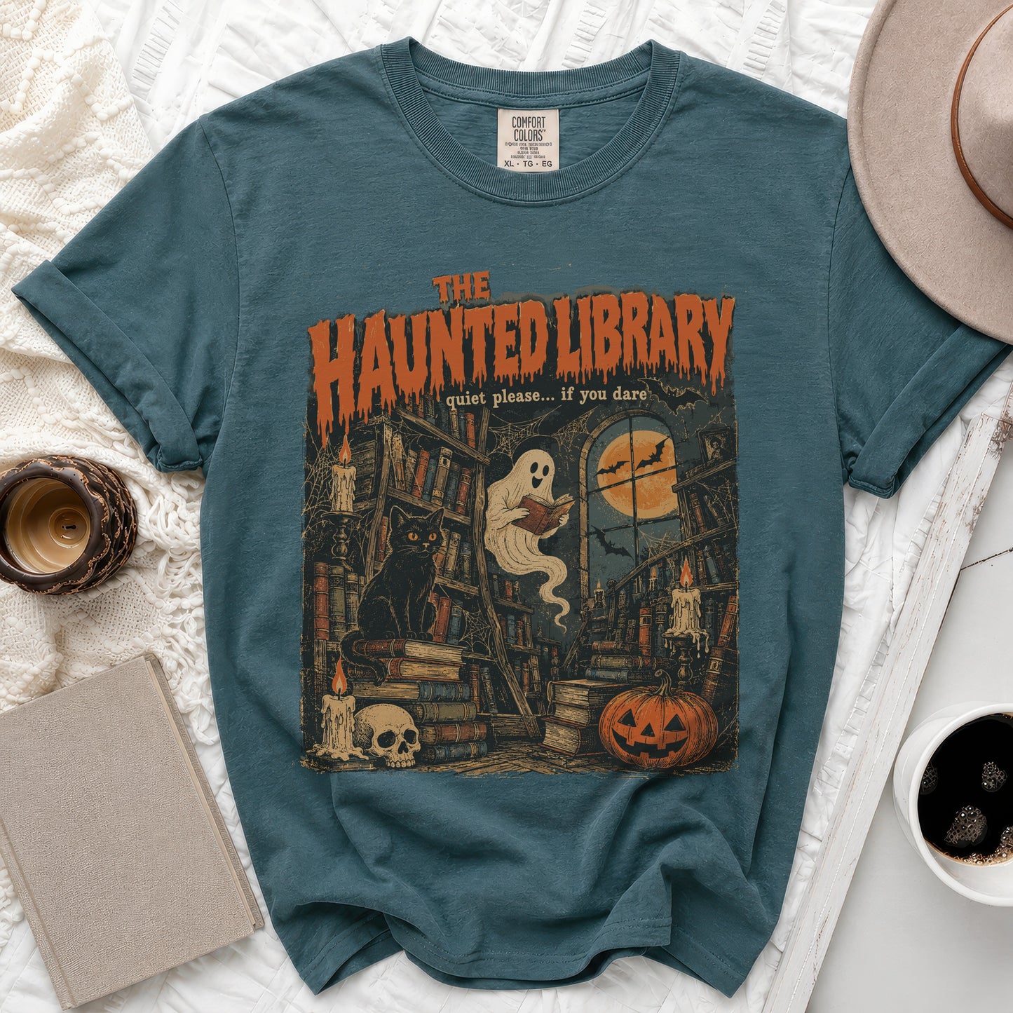 Teal t-shirt with "The Haunted Library" graphic: ghost, books, cat, skull, pumpkin.