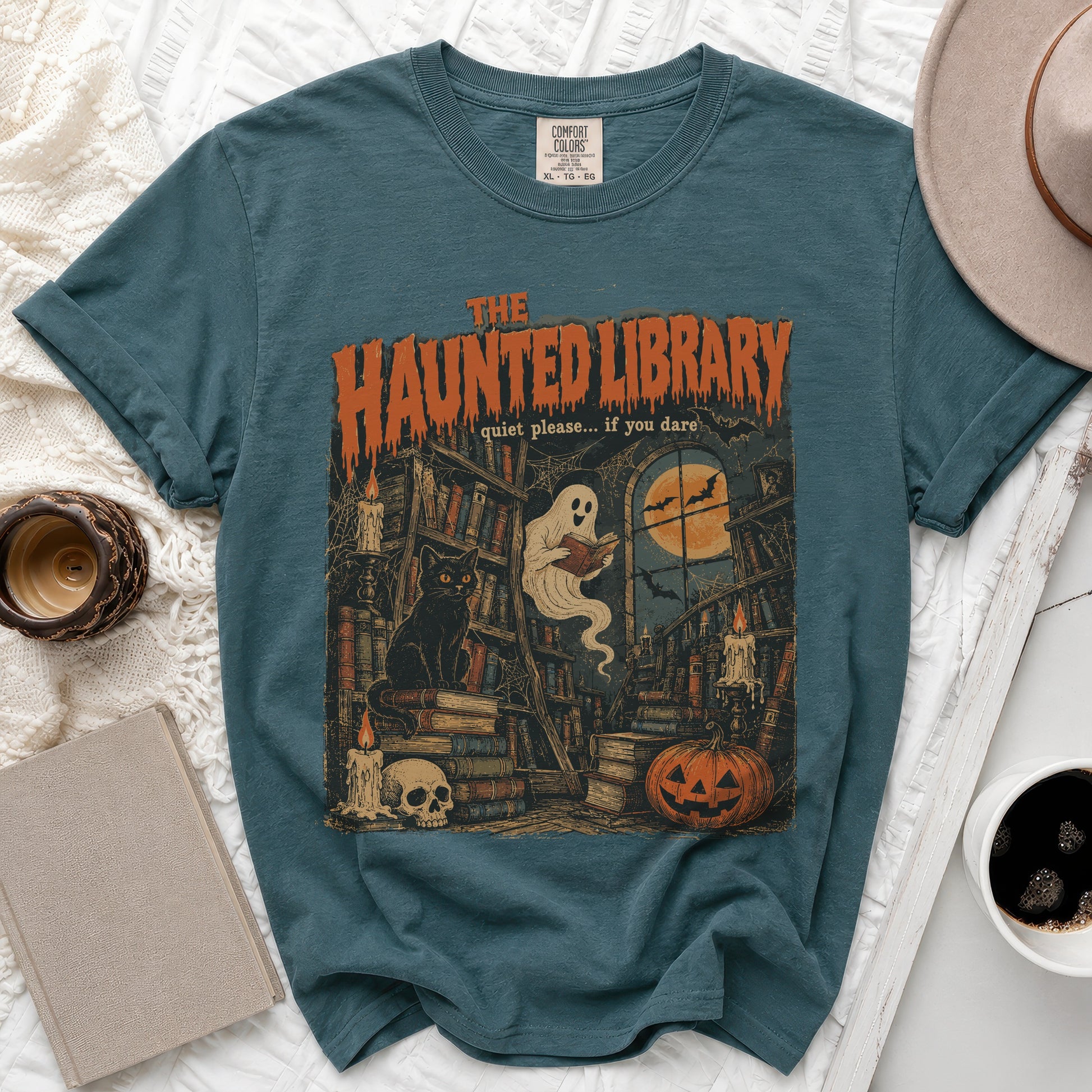 Teal t-shirt with "The Haunted Library" graphic: ghost, books, cat, skull, pumpkin.