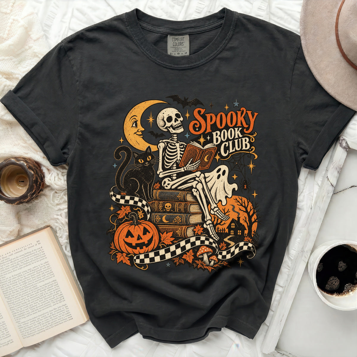 Skeleton reading book with "Spooky Book Club" text, moon, cat, pumpkin.