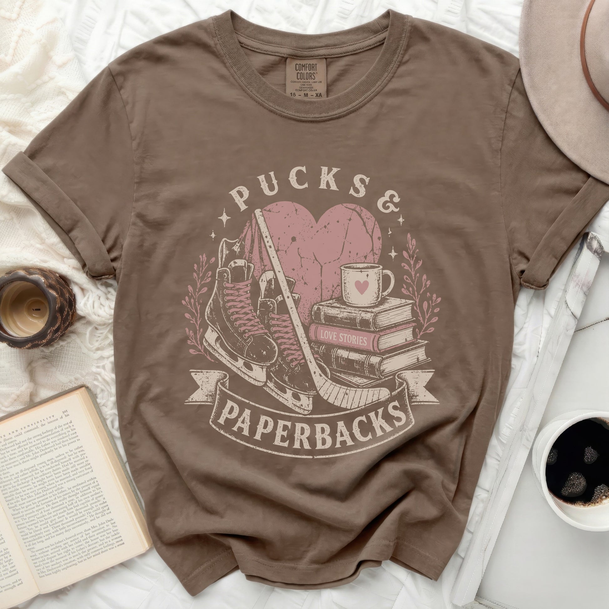 Brown t-shirt with "Pucks & Paperbacks" and heart graphic.
