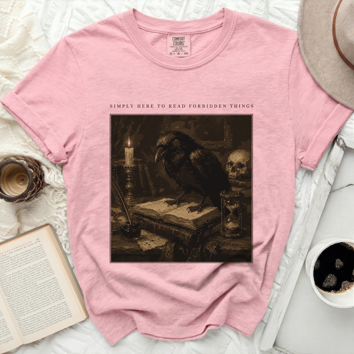 Pink t-shirt with "Simply Here to Read Forbidden Things" text and crow graphic.