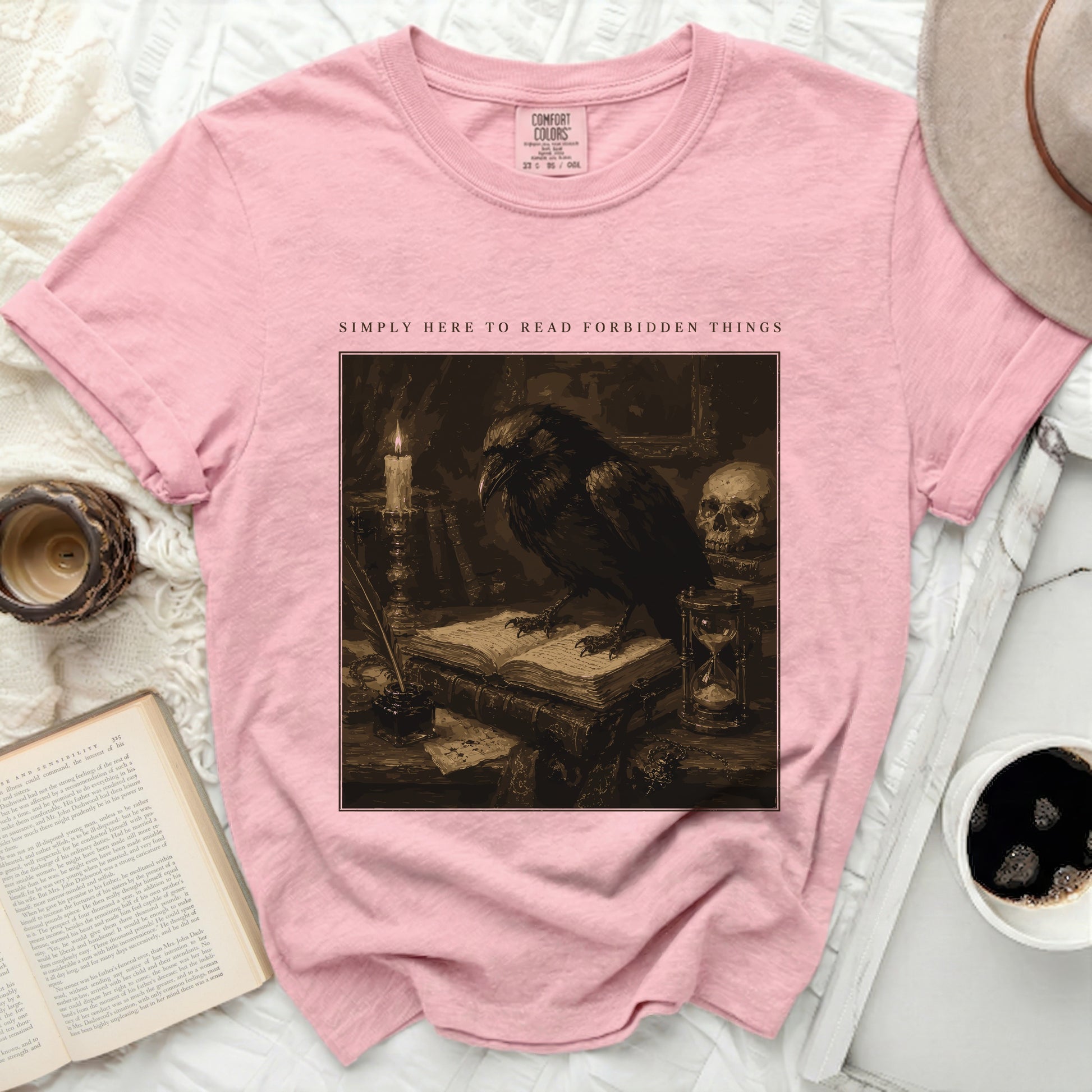 Pink t-shirt with "Simply Here to Read Forbidden Things" text and crow graphic.
