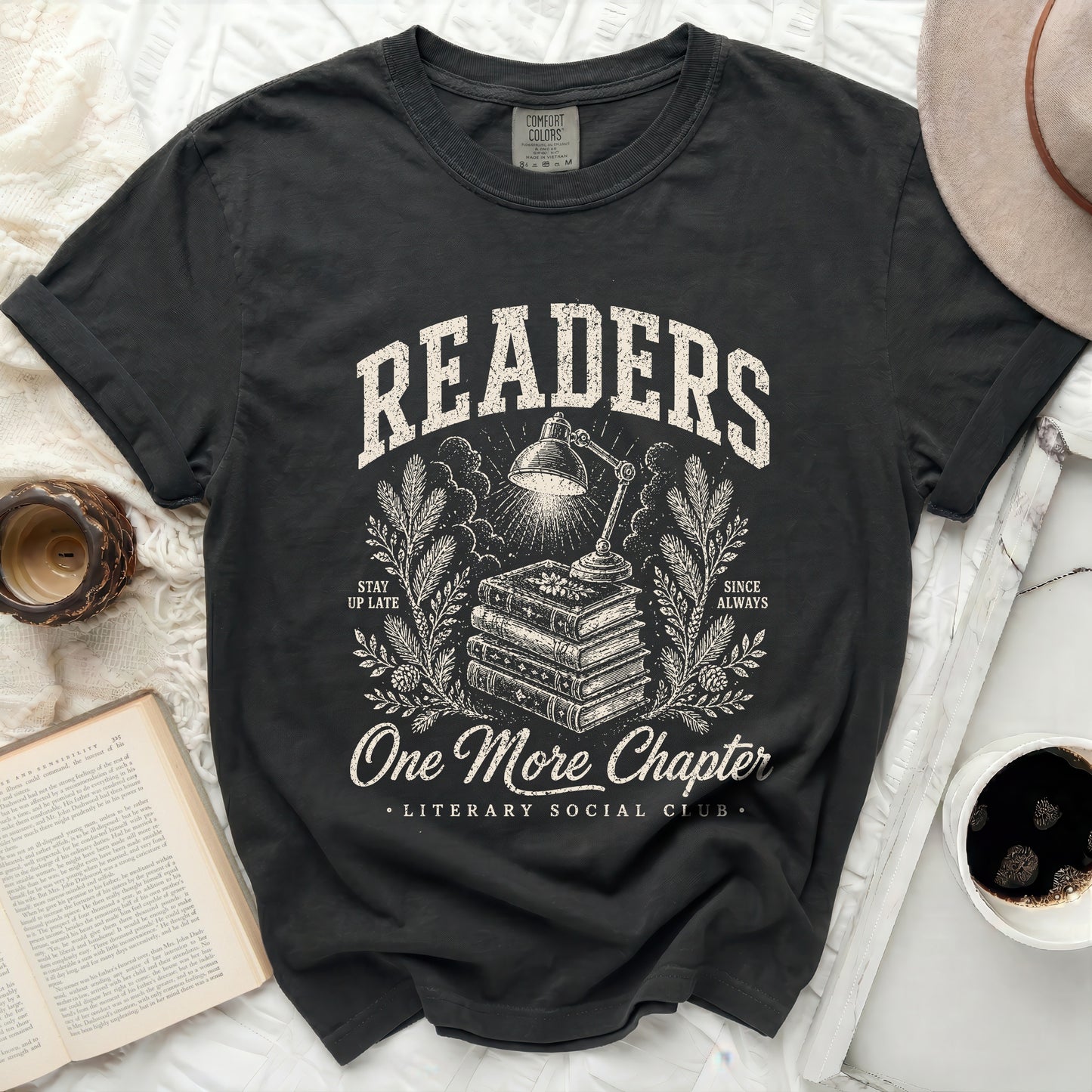 Dark t-shirt with "Readers One More Chapter" literary design.