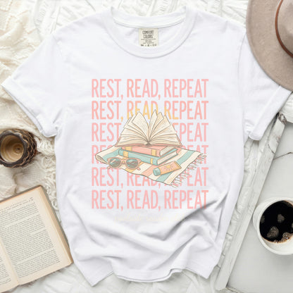 White t-shirt with "REST, READ, REPEAT" text and book graphic.