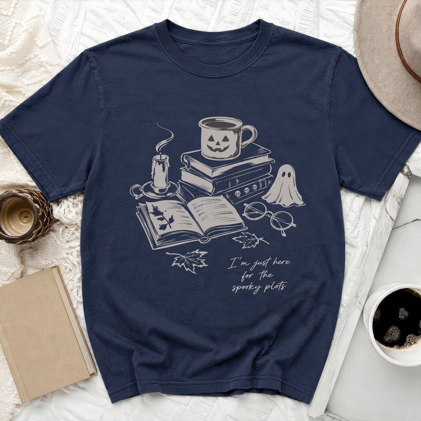 T-shirt with spooky plot illustration: ghost, books, candle, and coffee cup.