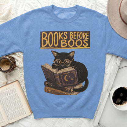 Light blue sweatshirt graphic of black cat reading books with "Books Before Boos" text.