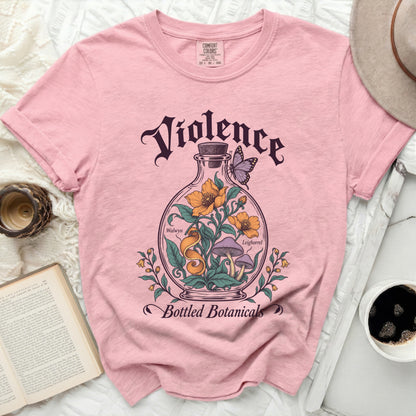 Pink short-sleeve t-shirt featuring a vintage graphic of a glass bottle containing flowers and mushrooms with butterfly and text.